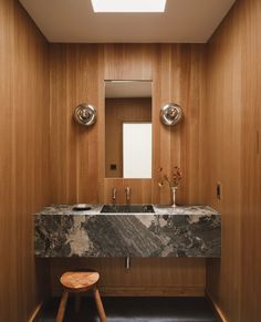 a marble sink and stool in a wooden bathroom with skylights above it on the ceiling