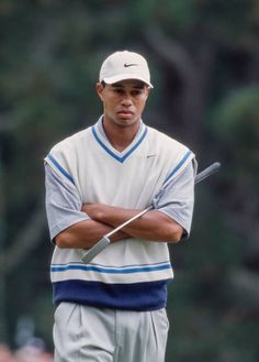 a man standing with his arms crossed in front of him and holding a golf club