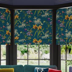 a living room filled with furniture and windows covered in roman shades that have colorful flowers on them