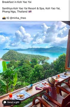 a table with food and drinks on it in front of a window overlooking the ocean