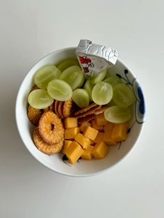 a bowl filled with fruit and crackers sitting on top of a white countertop