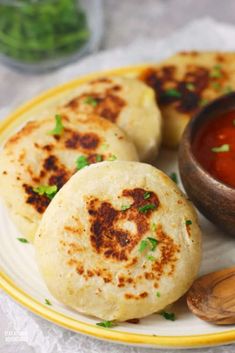 some food is sitting on a plate next to a bowl of sauce and two tortillas