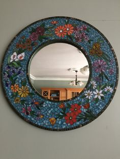 a round mirror with flowers painted on the side and an image of a room in the background