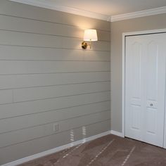 an empty room with two white doors and a light on the wall above it,