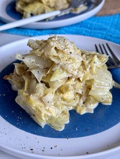 a white plate topped with cabbage covered in gravy next to a fork and knife