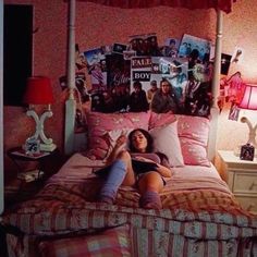 a woman laying on top of a bed in a bedroom next to a red lamp