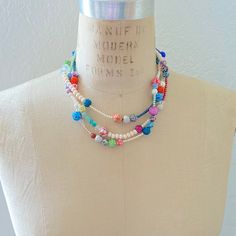 Achieve that stacked look effortlessly with this boho chic style multi-strand bib necklace. An artful mix of beads in vibrant colors and materials, such as glass beads, floral fimo, and faux pearls are strung on 3-strands that have been twisted for a fuller attention-grabbing stacked layered look. Lobster clasp. Handmade in USA. Bohemian White Multi-strand Layered Necklace, Whimsical Multicolor Beaded Chain Jewelry, Whimsical Multicolor Beaded Necklaces, Adjustable Multicolor Beaded Layered Necklace, Double Strand Colorful Beaded Necklaces For Layering, Multi-strand Beaded Necklace With Large Beads, Bohemian Multicolor Beaded Necklaces For Layering, Multicolor Double Strand Bohemian Layered Necklace, Multicolor Double Strand Layered Necklace