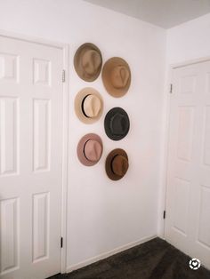 several hats are hanging on the wall in a room with white doors and carpeting