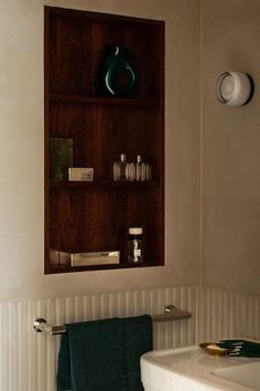 a white sink sitting under a bathroom mirror next to a shelf filled with soap and toothbrushes