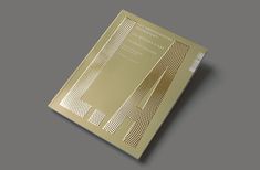 an open book with gold foil on the front and back cover, sitting on a gray surface