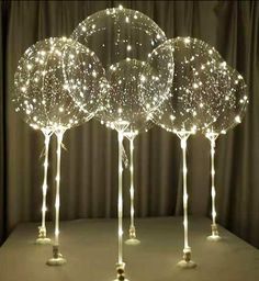 three lighted balls on top of each other in the shape of trees with long legs