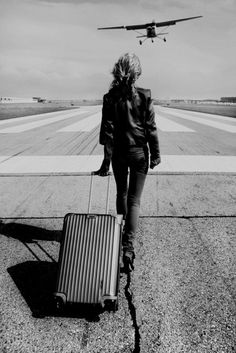 a woman is walking towards an airplane on the tarmac with her suitcase in hand