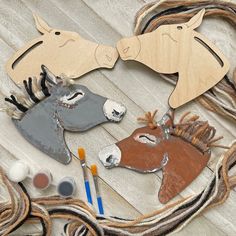 two wooden horses are sitting next to some paintbrushes and other crafting supplies