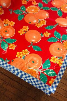 an orange table cloth with flowers and leaves on it, sitting on a wooden floor