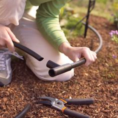 a person kneeling down with gardening tools on the ground