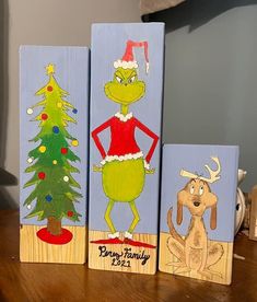 three wooden blocks decorated with paintings of christmas trees and dr seuss the cat in the hat