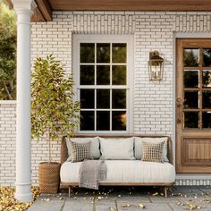 a white couch sitting on top of a stone floor next to a wooden front door