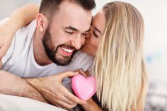 a man and woman cuddling over a pink heart