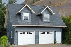 a two car garage with three windows in front of a mountain