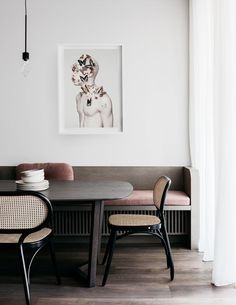 a dining room table with two chairs and a painting hanging on the wall above it