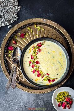 a bowl filled with soup and garnished with flowers on a plate next to a spoon