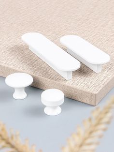 three white knobs sitting on top of a beige mat next to a plant and two other items