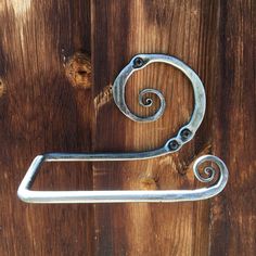 a metal handle on a wooden door that is shaped like a letter s with swirls