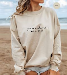 This custom Grandma Sweatshirt is the perfect gift for any proud grandmother! Personalize it with the names of her beloved grandkids to make it truly special. Whether she goes by Grammy, Mimi, Gigi, or Nana, this cozy sweater will warm her heart every time she wears it. Give her a meaningful present that celebrates her well-deserved promotion to Grandma, and make her smile every time she puts it on. Surprise her with this thoughtful and unique gift that she will cherish for years to come. PRODUC Personalized Casual Crew Neck Tops, Personalized Casual Long Sleeve T-shirt, Casual Personalized Long Sleeve T-shirt, Personalized Long Sleeve Casual T-shirt, Casual Long Sleeve Personalized T-shirt, Personalized White Long Sleeve Tops, Personalized Relaxed Fit Casual Tops, Personalized Long Sleeve White Tops, Personalized White Casual Sweatshirt