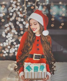 a girl in a santa hat is holding a gift