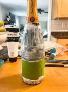 a bottle that is sitting on top of a table with some paint and pencils