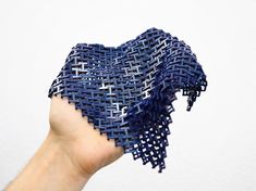 a hand holding up a piece of blue woven material in the shape of a heart