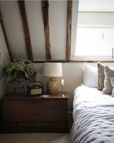 a bedroom with white bedding and wooden beams