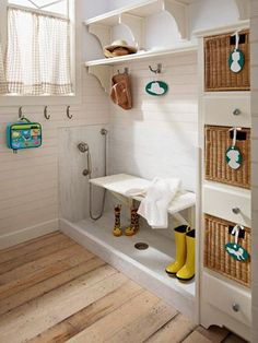 a white bathroom with yellow rubber boots on the floor and shelves above the shower area