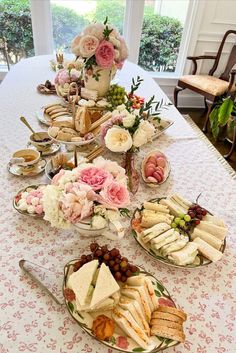 a table topped with plates filled with sandwiches and desserts next to a vase full of flowers