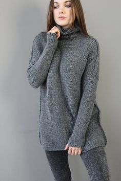 a woman in grey sweater and leggings posing for the camera with her hand on her chin