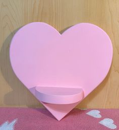 a pink heart shaped shelf on top of a table