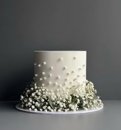 a white wedding cake with flowers on the top and bottom is sitting on a platter