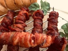 bacon skewers on a wire rack next to bread and green leafy leaves