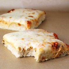 two pieces of pizza sitting on top of a table next to each other with cheese and sauce