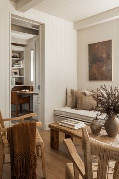 a living room filled with furniture next to a wooden table and white painted walls on the wall