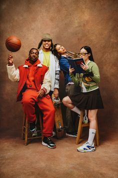 three people are posing for a photo with a basketball in front of them and one is holding a book