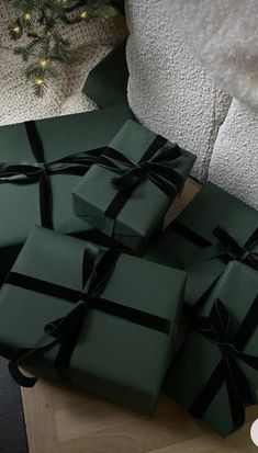 a pile of wrapped presents sitting on top of a wooden table next to a christmas tree