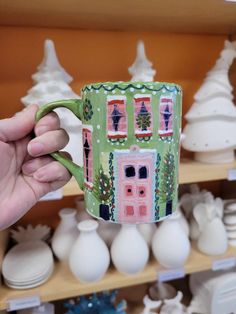 a person holding up a coffee mug in front of shelves