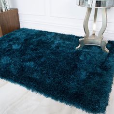 a blue shaggy rug on the floor next to a table with a mirror in it