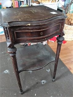 an old wooden desk sitting on top of a hard wood floor next to a pile of books