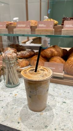 a cup of coffee sitting on top of a counter next to some croissants