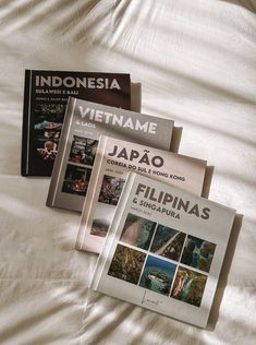 three books laying on top of a bed next to each other