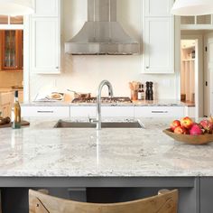 a bowl of fruit is sitting on the kitchen counter top next to an oven and sink