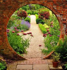 an archway in the middle of a garden filled with flowers