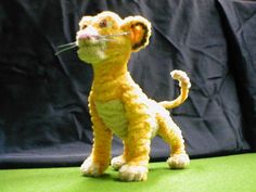 a stuffed animal that looks like a lion is standing on a green surface next to a black background